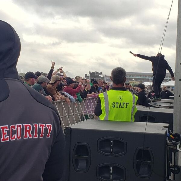 Security and staff working the stage barricade line at an outdoor concert