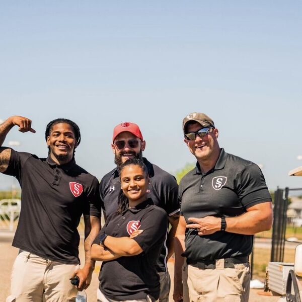 Four uniformed Semper Secure officers standing together at an outdoor event site